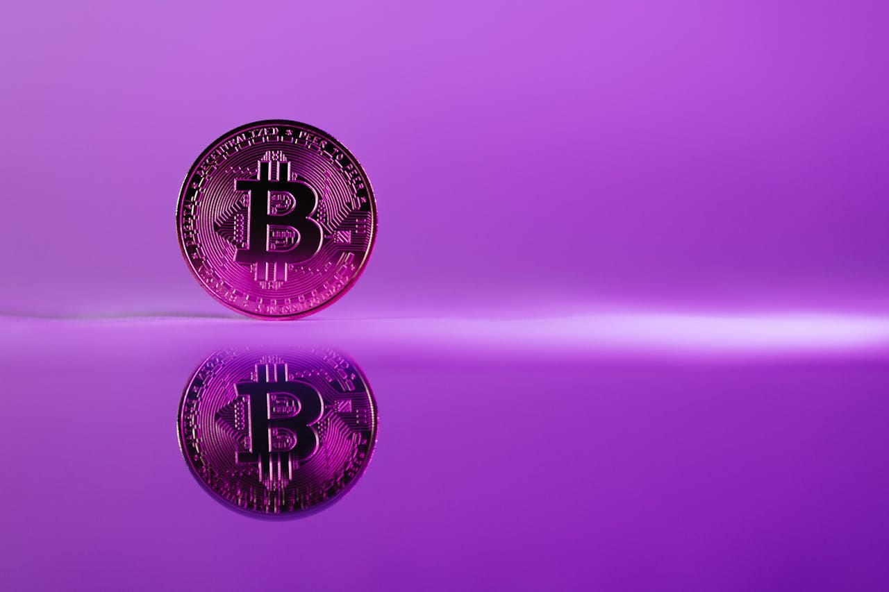 A striking image of a Bitcoin coin reflecting on a glossy surface against a vibrant purple background.